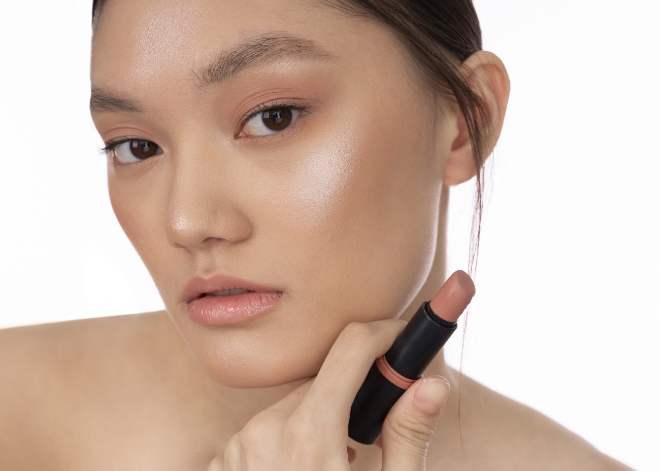 Jovem usando um batom nude cremoso 