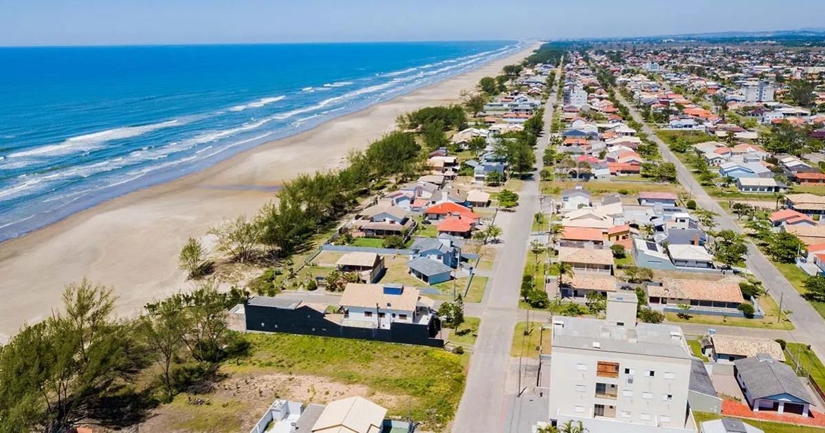 Imagem de Balneário esplanada vindo de cima, focando na região com pequenas moradias, e na pequena faixa de areia, para fazer relação com o fato de que é uma das praias mais habilitadas e que surpreende pelas águas cristalinas