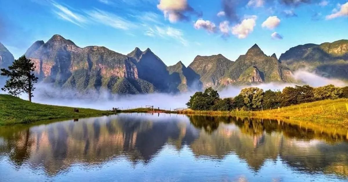 Imagem de montanhas, com um lago no centro e um céu azul, para mostrar para os leitores como é um dos espaços do Parque Estadual da Serra Furada
