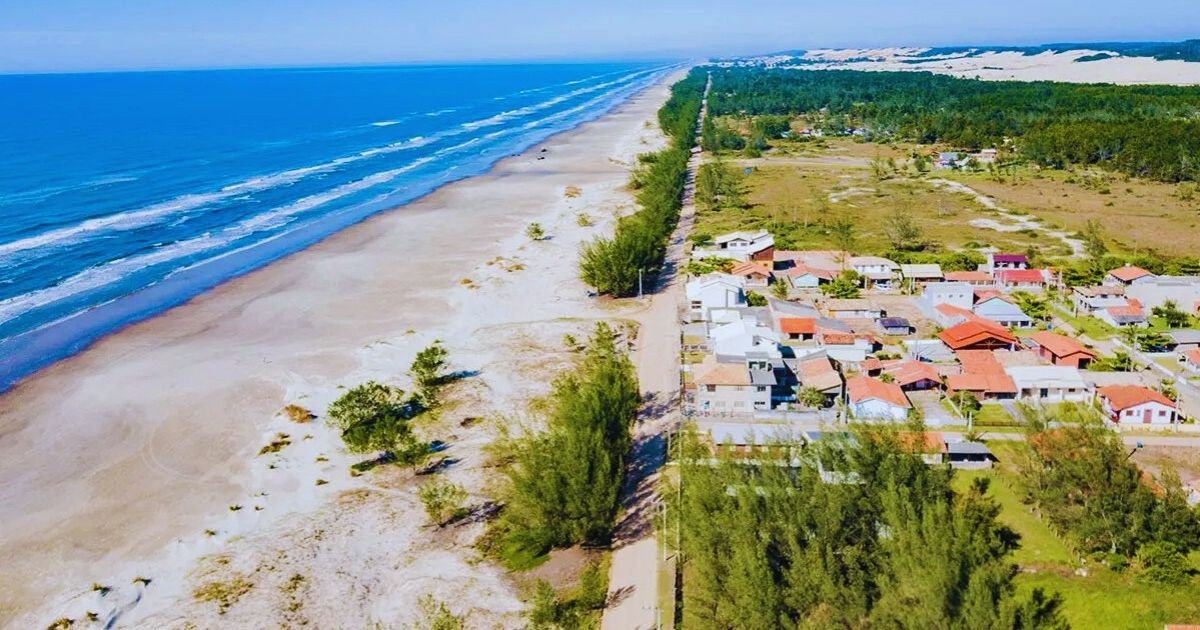 Imagem de Balneário Figueirinha vista de cima, mostrando a vegetação nativa e poucas casas ao redor, para fazer referência ao fato de que a paisagem possui mais de 4 km de orla