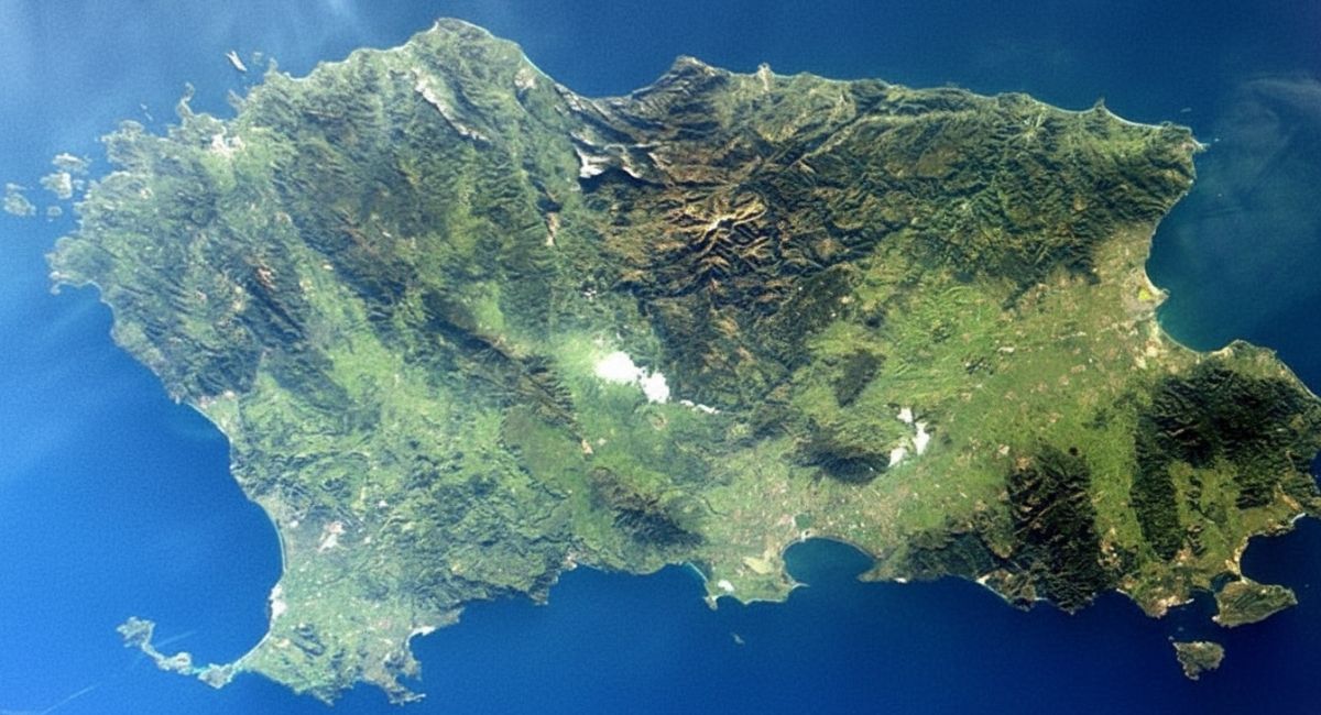 Vista aérea da ilha italiana paradisíaca da Sardenha, cercada por um mar azul intenso. A paisagem mostra montanhas verdes, áreas planas e pequenas baías que revelam a diversidade natural da região