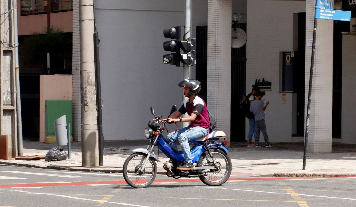 na foto aparece uma pessoa de moto usando capacete e que deverá mostrar a CNH a partir de janeiro de 2026 