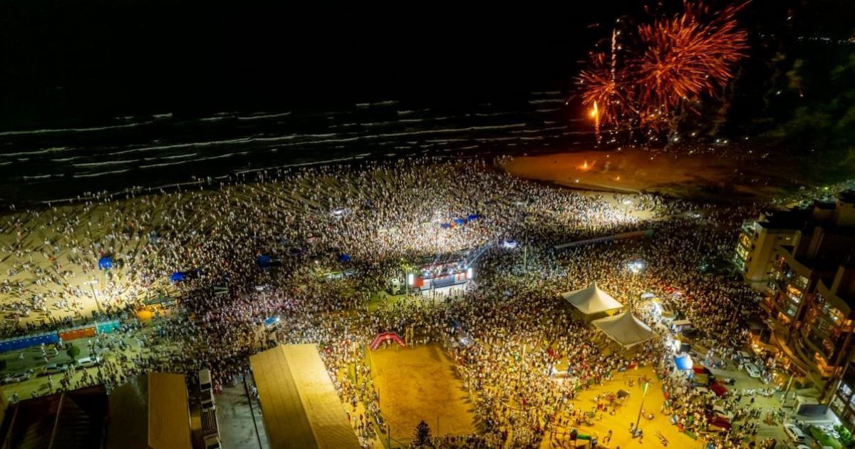 Imagem aérea do ano novo de Laguna, com show perto da praia, com uma multidão de pessoas, para relacionar com o fato de que a cidade costuma atrair mais de 150 mil pessoas nesta data 