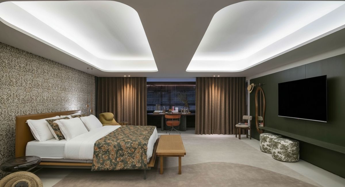 Quarto de hotel moderno e bem iluminado, com cama grande, cortinas fechadas e ambiente projetado para reduzir o barulho da rua.