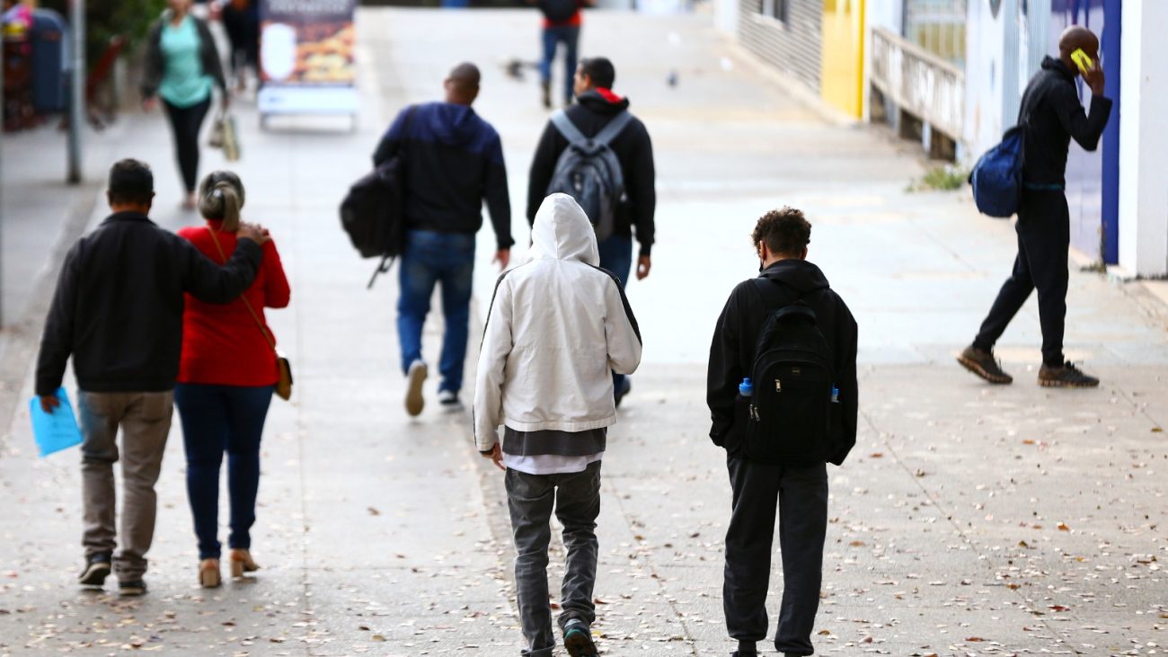 Pessoas encapuzadas andando por rua para matéria sobre massa de ar frio
