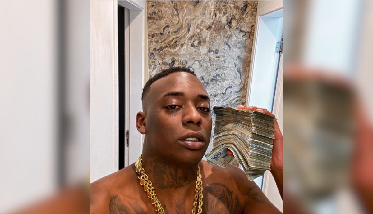 Mc Negão Oficial posa segurando maço de dinheiro em ambiente interno