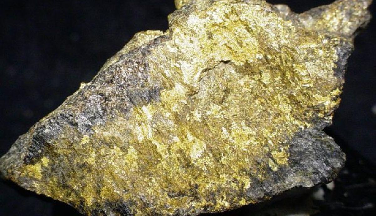 Rocha com ouro bruto extraído da montanha em destaque sobre fundo escuro