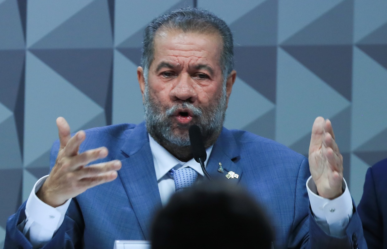 carlos lupi é um homem grisalho, com barba e que veste terno azul. ilustra matéria sobre fraude no inss e operação sem desconto