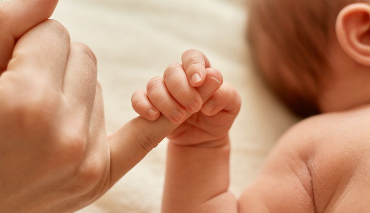 Mão e corpo de bebê com a mãe