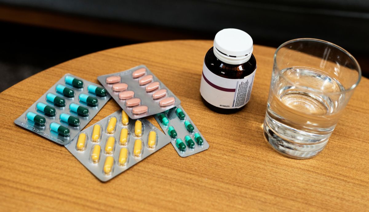 remédios em cima da mesa com um copo d'água