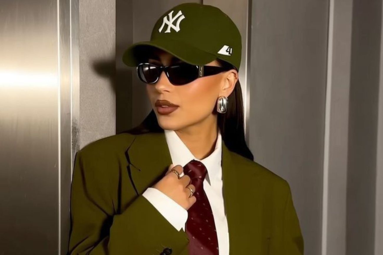 Jovem de terno e boné verde usando um óculos de sol de forma moderna 