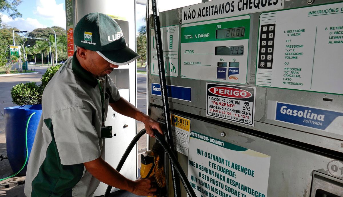 Frentista manuseando uma bomba de combustíveis