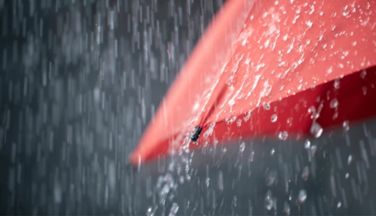 Guarda-chuva vermelho sob chuva intensa ilustra os impactos da frente fria associada a ciclone, que aumenta o risco de temporais e elevados volumes de precipitação.