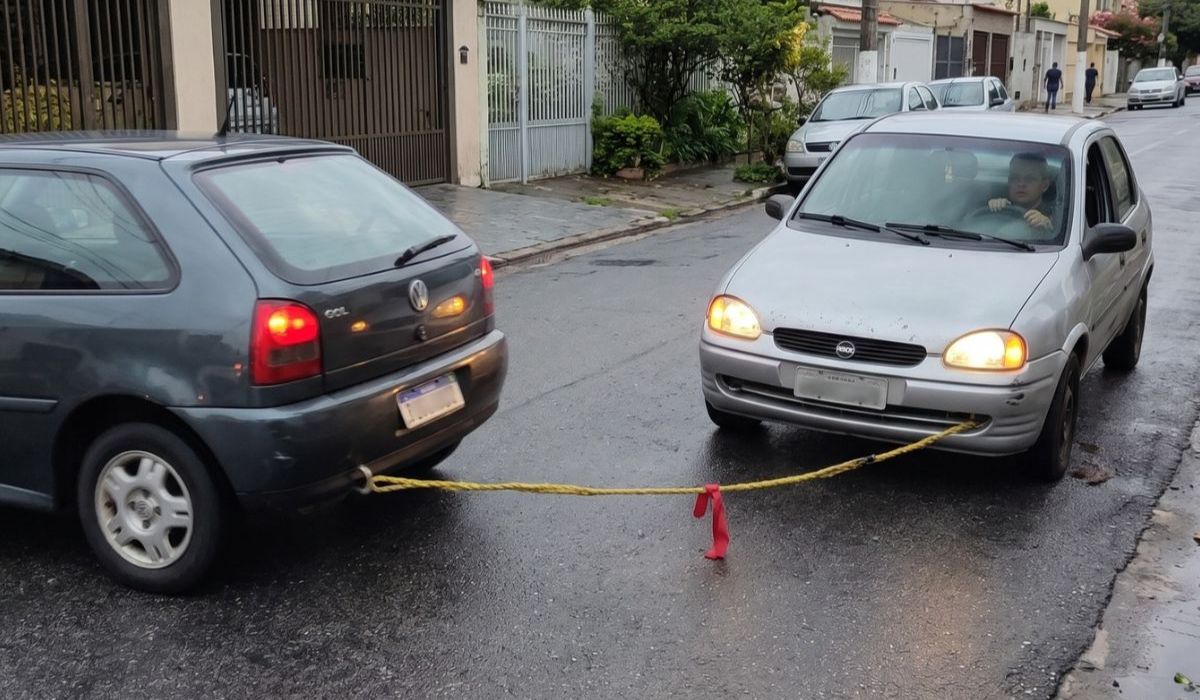 na foto aparece um carro que rebocar carro com corda em uma situação ilegal na cidade